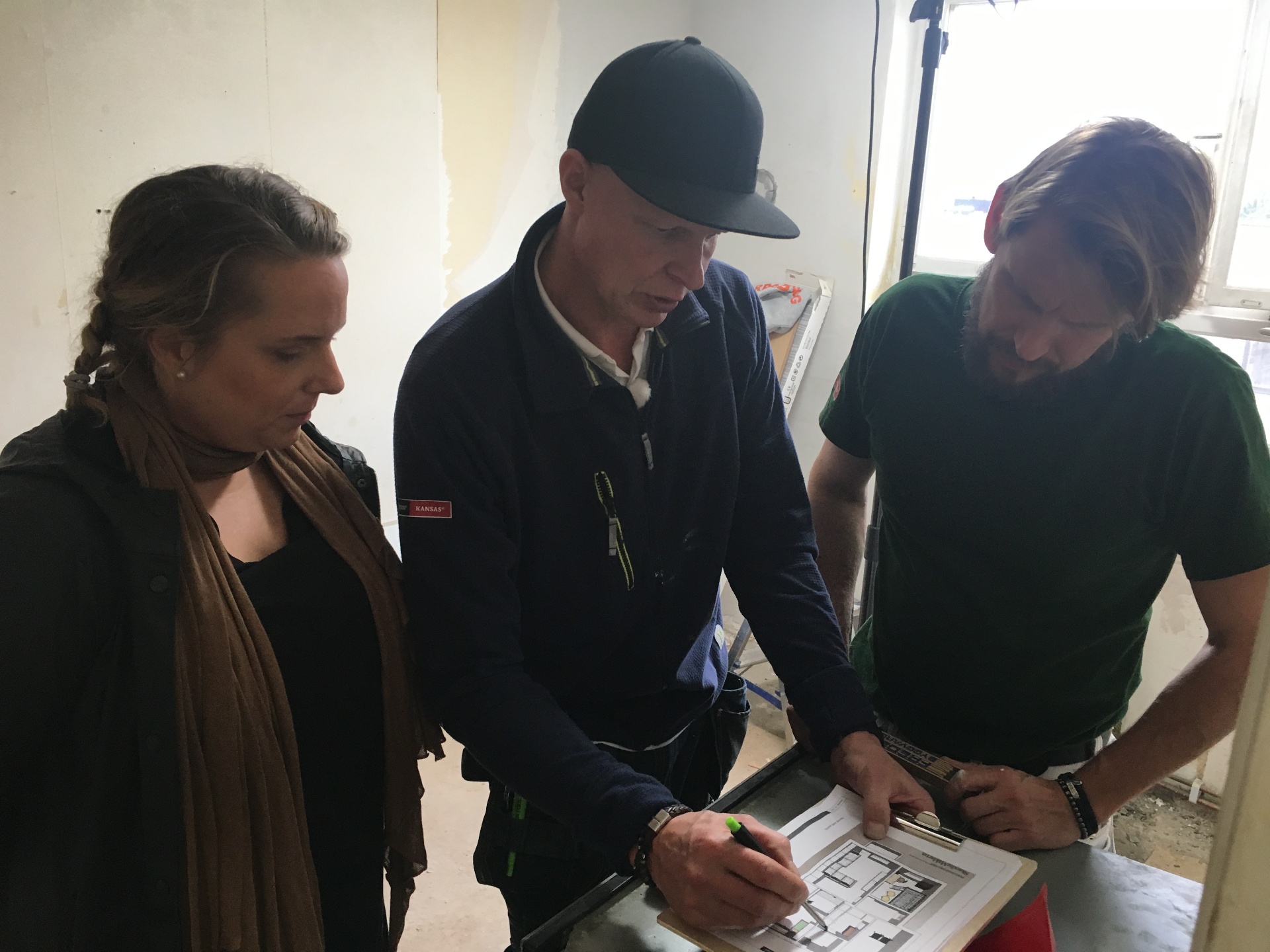 Johanna Wåhlander går igenom ritningar med hantverkare på byggarbetsplatsen